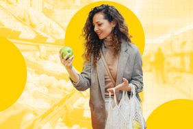 A person selecting an apple while holding a shopping bag in a store