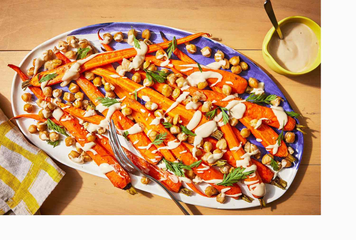 oven-roasted carrots with garbanzo beans and tahini on a platter with linen and serving fork