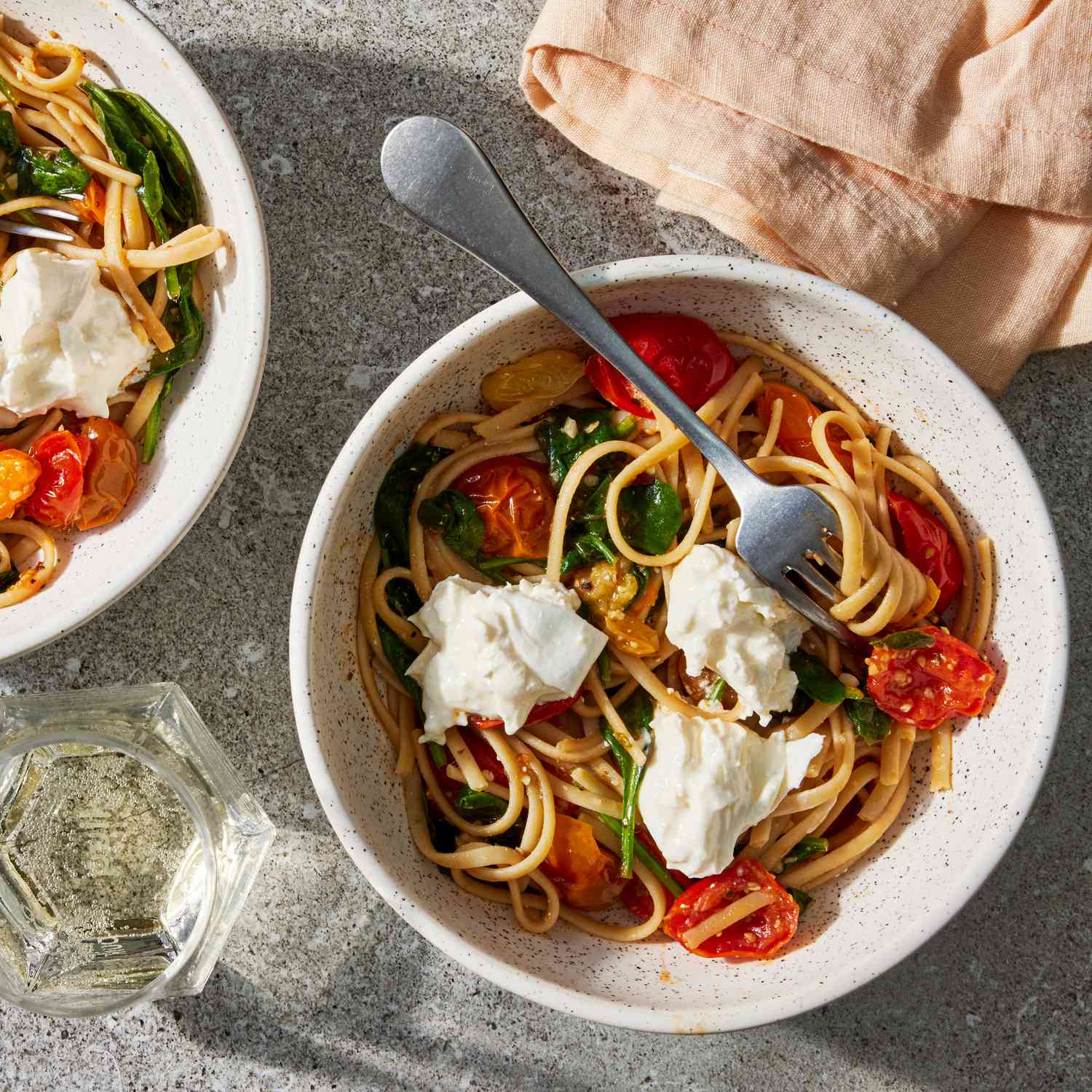 Overhead view of two stone bowls of Burrata Pasta with Cherry Tomatoes & Spinach recipe