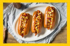 Carrot hotdogs in buns on a white plate with a blue and white dish towel and wood surface