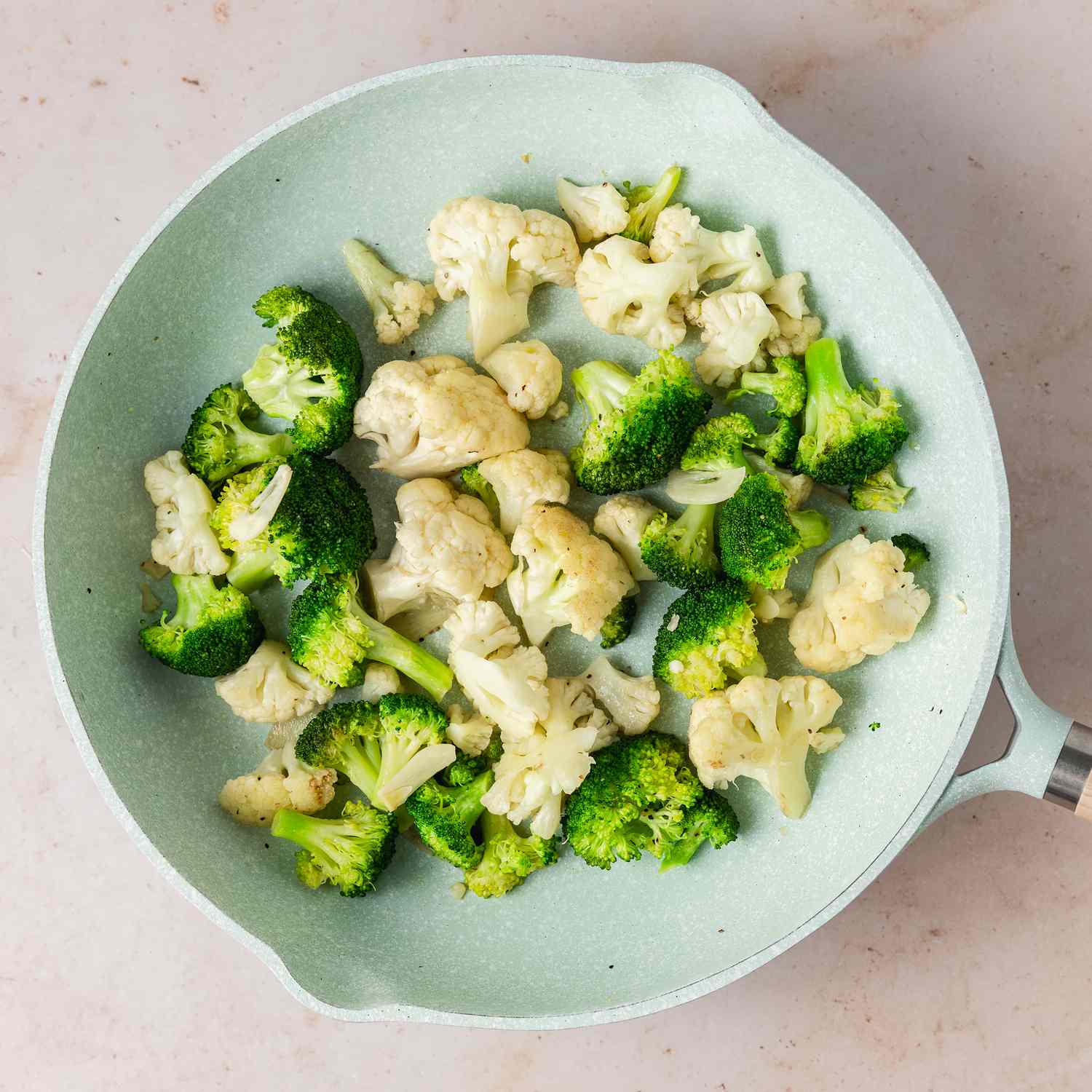 overhead view of cooked chopped broccoli and cauliflower in a pan