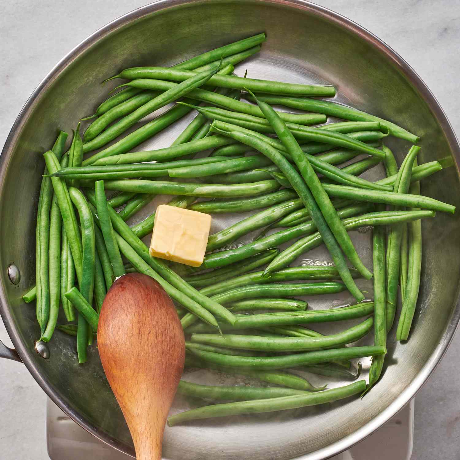Green beans in a frying pan with a square of butter added