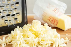 grater, stick of butter, and grated butter on a board