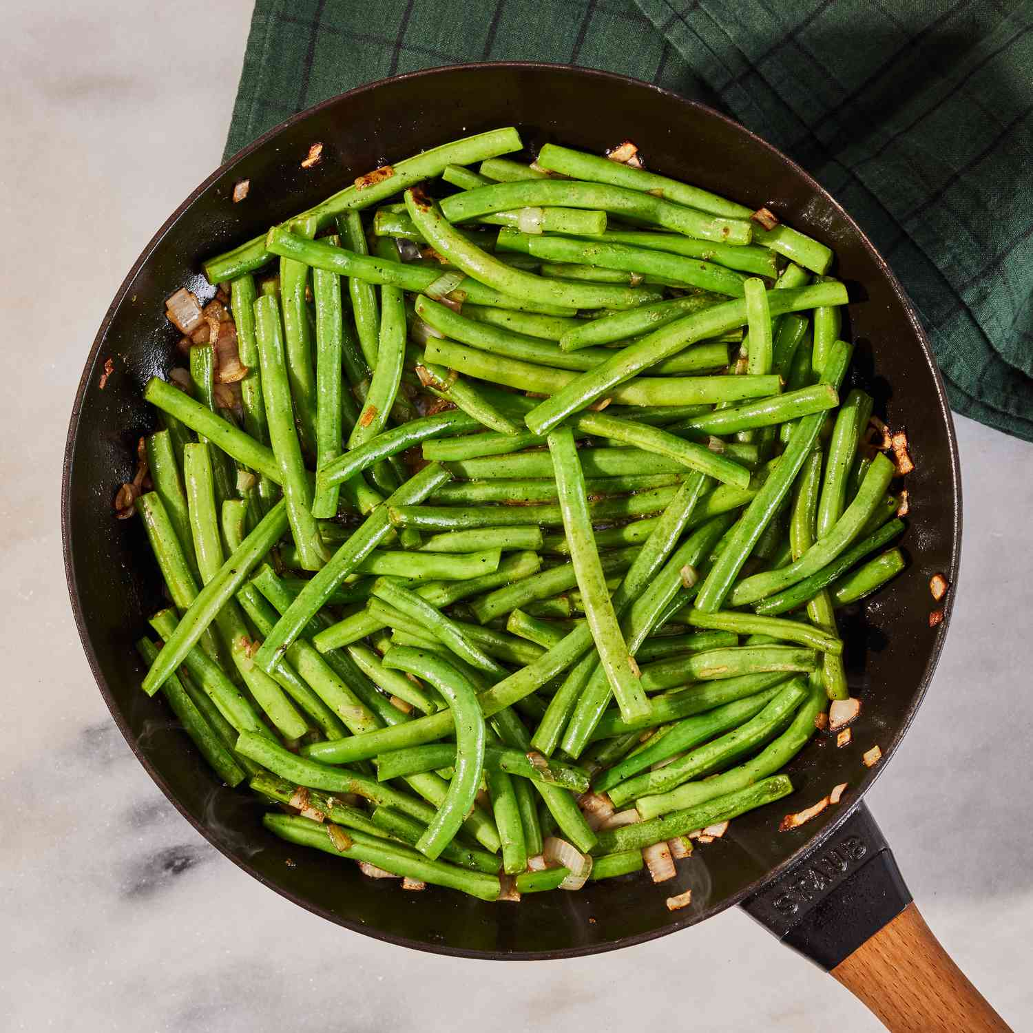 a photo of the green beans and shallot added into the cooked bacon