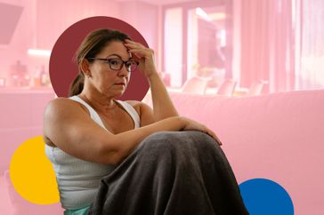 a photo of a woman sitting on a couch holding her head and looking stressed