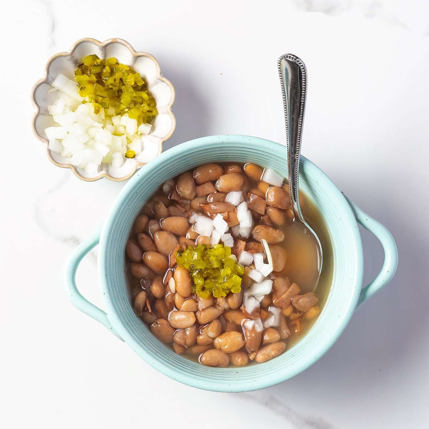 overhead view of Soup Beans in a bowl garnished with finely chopped onions and relish