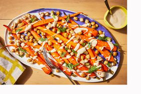 oven-roasted carrots with garbanzo beans and tahini on a platter with linen and serving fork