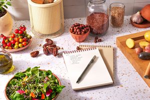 Notebook with a shopping list , salad, dates, tomatoes