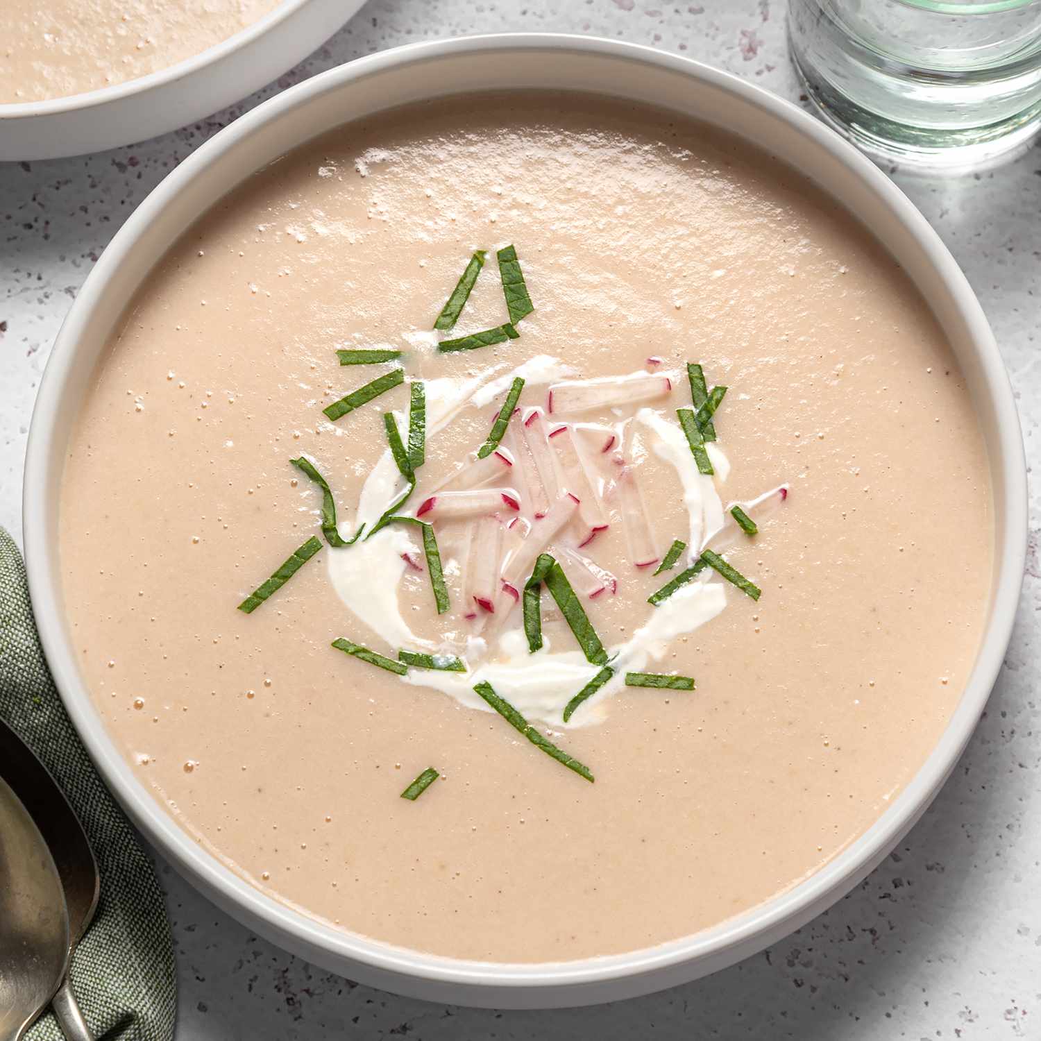Overhead view of a white bowl of Creamy Radish Soup recipe