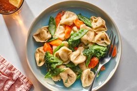 Overhead view of a blue serving plate of Tortellini Primavera recipe with a fork