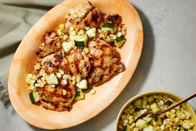 Overhead view of an orange plate of Grilled Honey-Mustard Chicken with Zucchini-Corn Relish recipe and a bowl of the relish