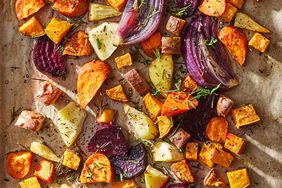 Sheet-pan roasted vegetables on a baking sheet topped with fresh herbs