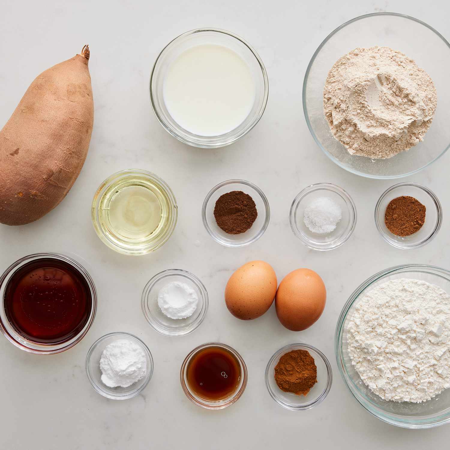 Overhead view of ingredients for Maple-Cinnamon Sweet Potato Bread recipe in various bowls on a marble counter