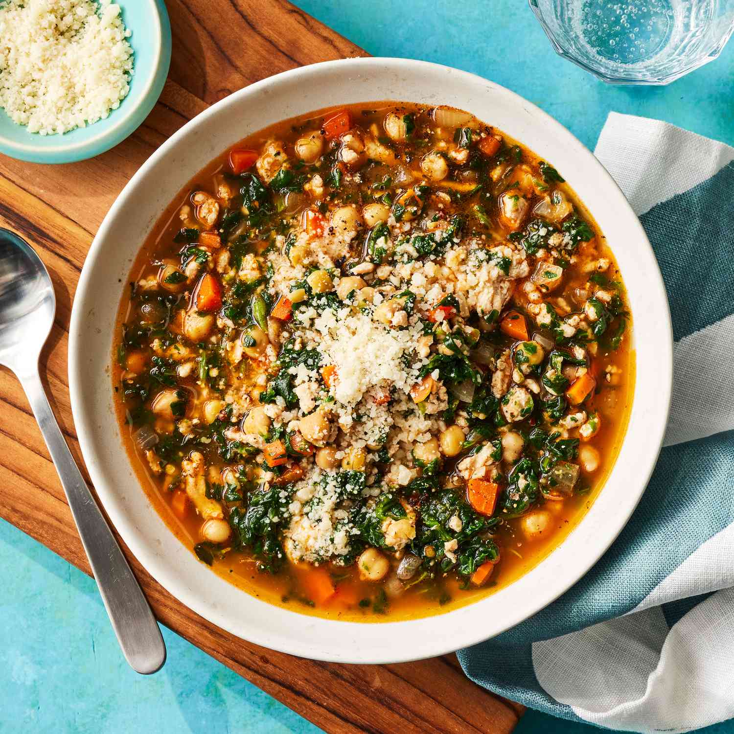 Hearty chickpea & spinach stew in a white bowl, with grated parmesan cheese sprinkled on top