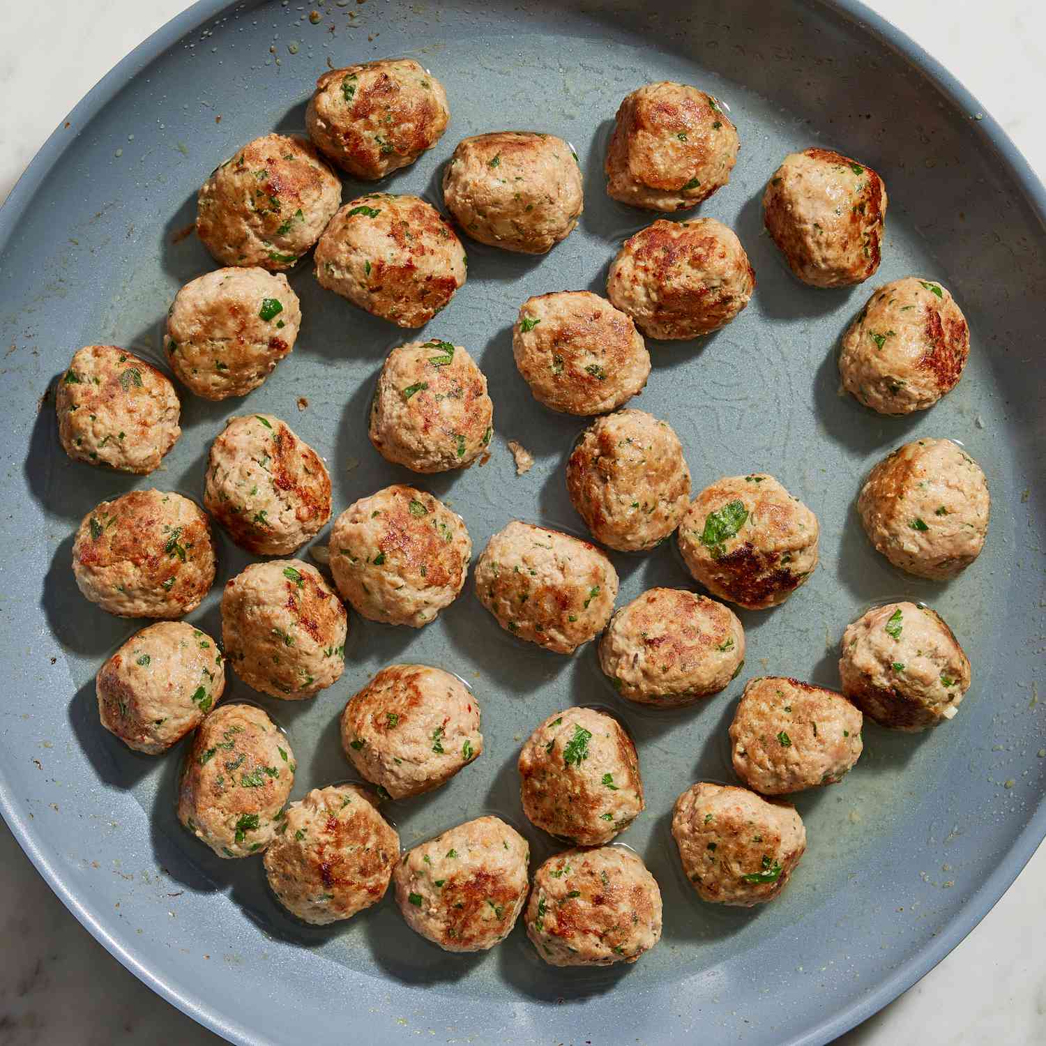Meatballs for the Italian wedding soup recipe in a blue frying pan