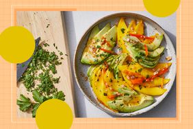 Plate of sliced mango and avocado with garnish, cutting board with chopped herbs on the side
