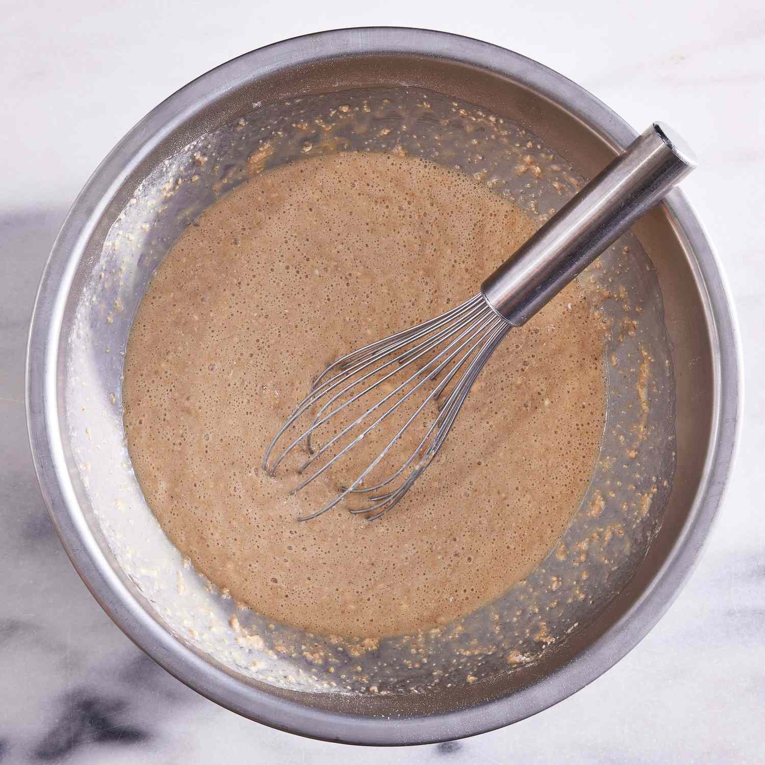 overhead view of waffle batter in a mixing bowl with a whisk