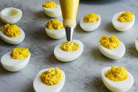 a hand squeezing a pastry bag with deviled egg filling