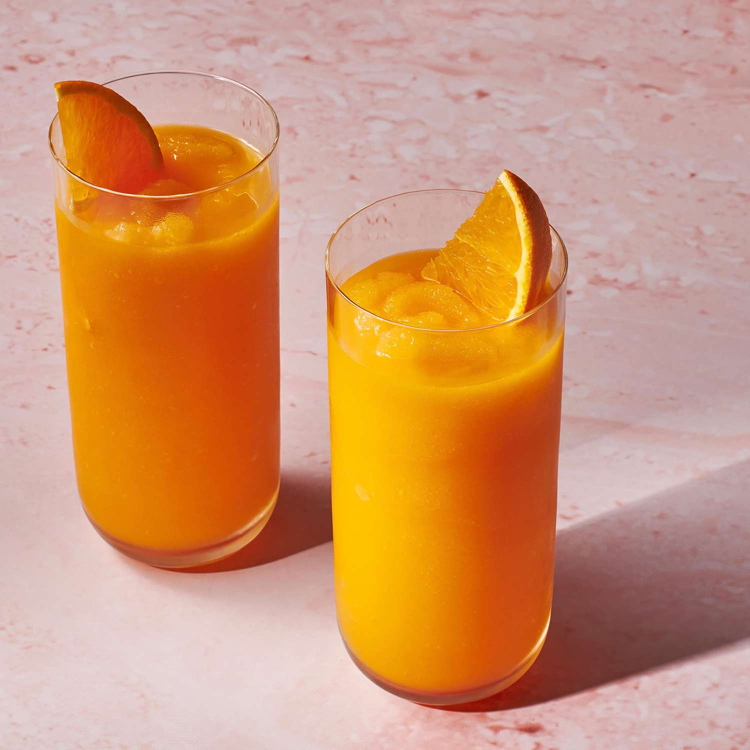 a recipe photo of the Carrot Smoothie served in two glasses with orange slices for garnish