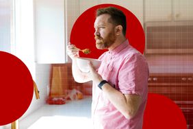 Man eating cereal while standing in a kitchen