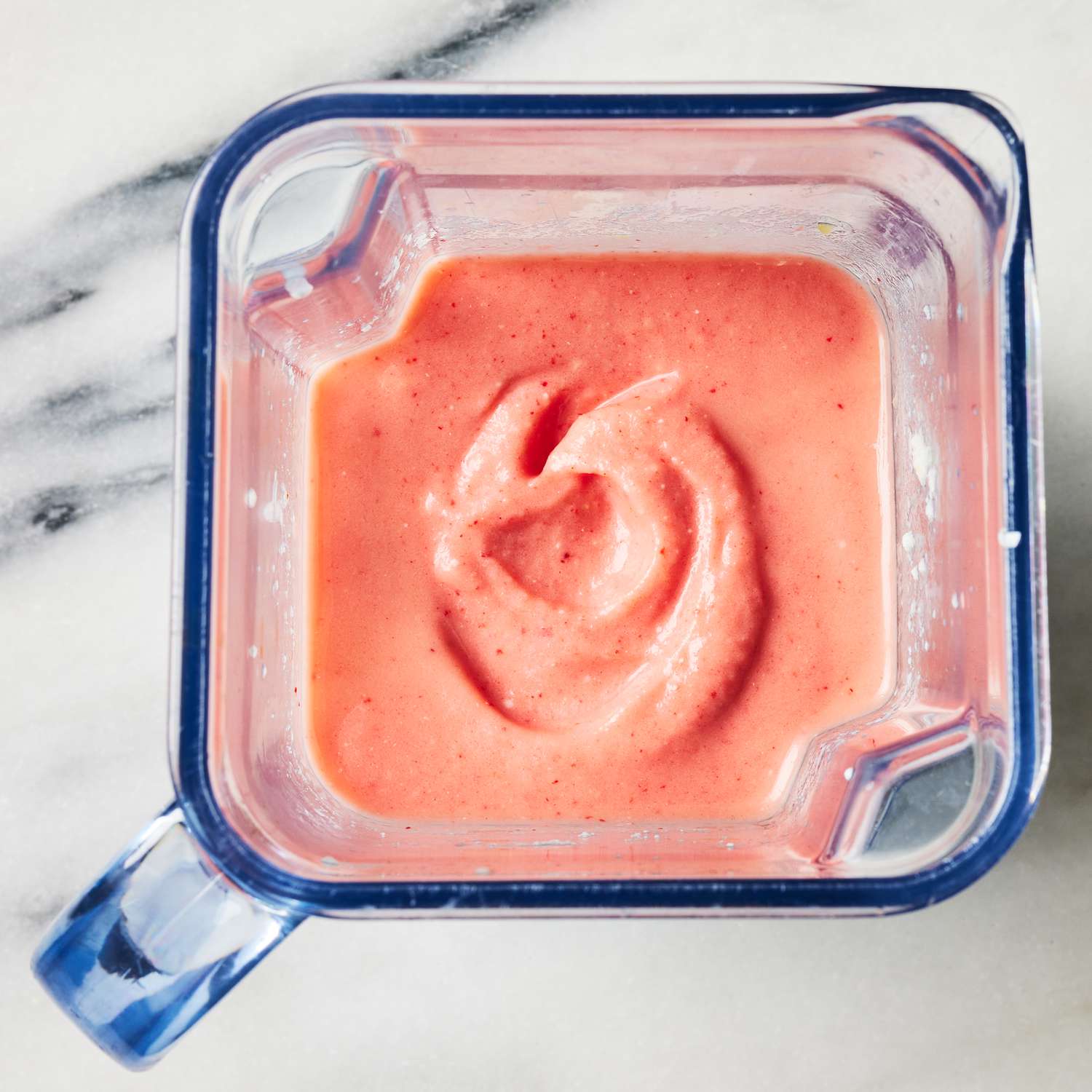 Ingredients for the no-sugar-added frozen strawberry piÃ±a coladas recipe blended in a blender