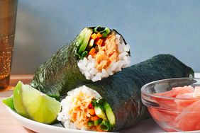 Spicy Salmon Sushi Roll-ups on a plate with a side of pickled ginger and a wedge of lime
