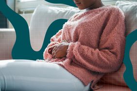 a photo of a woman grasping her midsection expressing pain from being bloated