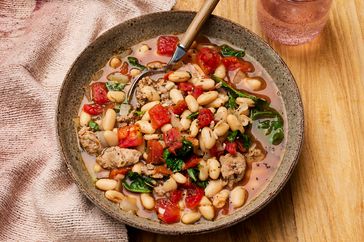 Overhead view of a stoneware bowl of White Bean-Sausage Soup recipe