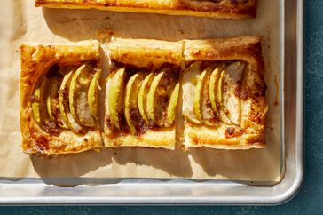 Apple tart made on puff pastry dough, on a parchment paper line baking sheet