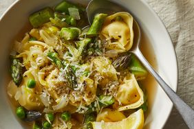 The easy tortellini soup recipe served in a white bowl, garnished with freshly grated Parmesan cheese
