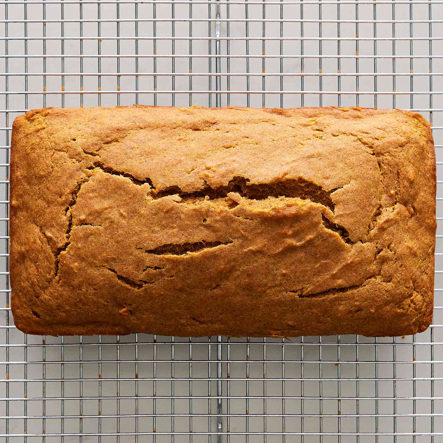 Overhead view of the cooked loaf on a cooling rack from Maple-Cinnamon Sweet Potato Bread recipe