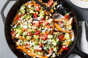 a cast iron skillet with sweet potatoes and various toppings