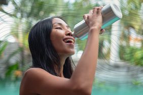 Woman drinking from a silver water bottle outdoors