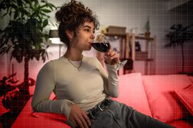 Person sitting indoors drinking from a wine glass