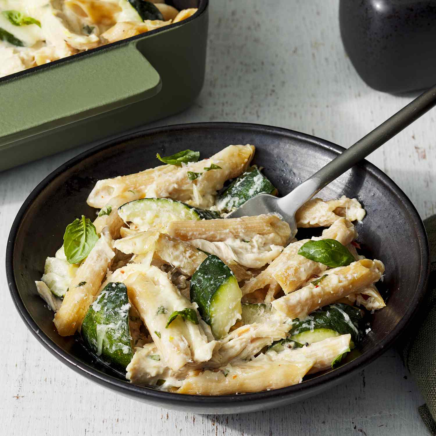 Angled view of a black plate of Creamy Zucchini & Rotisserie Chicken Pasta Bake recipe