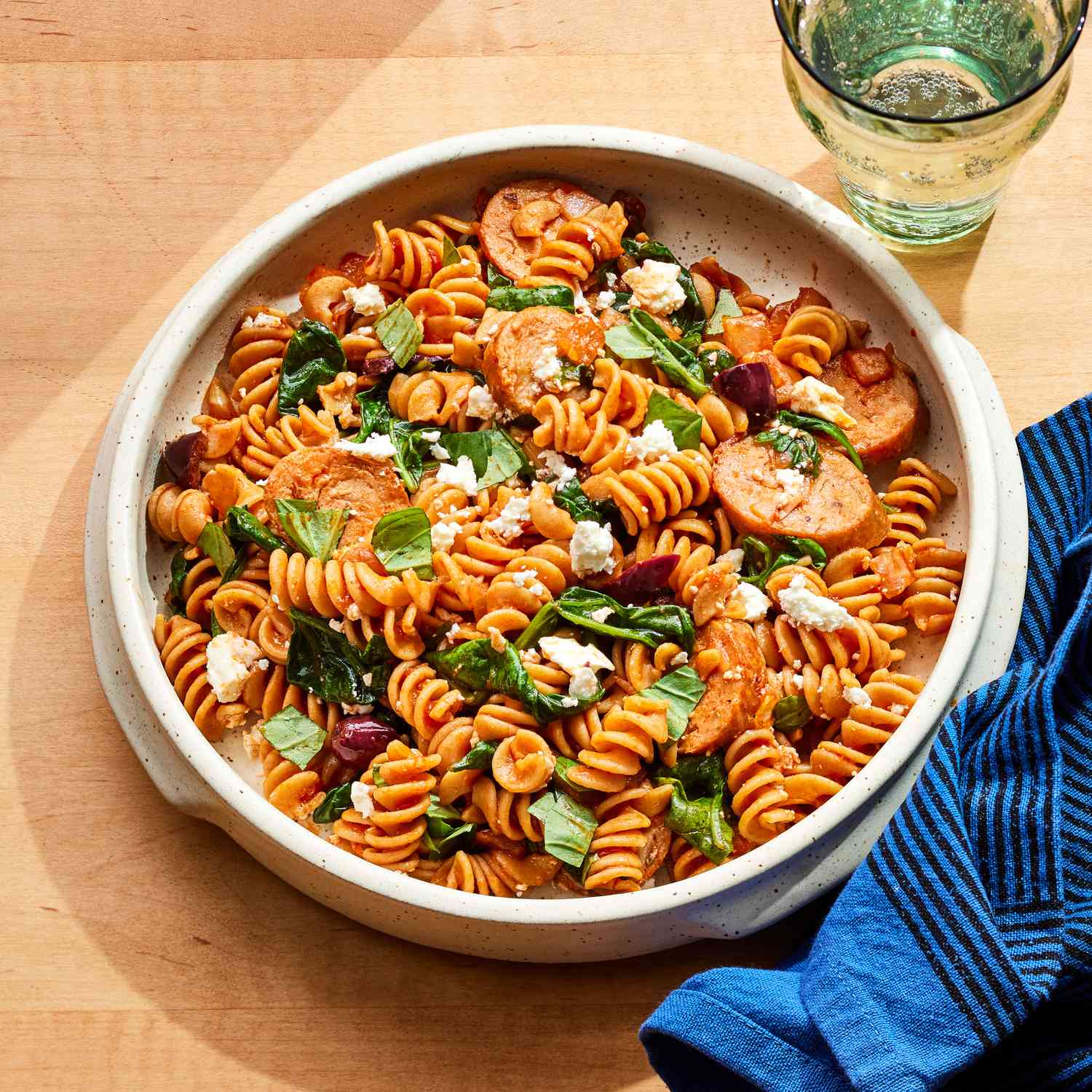 A white plate with a serving of the one-pot spinach, chicken sausage & feta pasta recipe