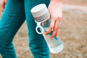women in jeans outside holding water bottle with white lid
