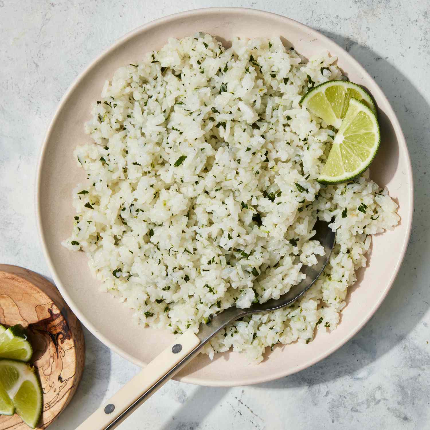 The easy cilantro-lime rice recipe served on a light pink plate and garnished with two lime wedges