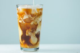 a photo of milk being poured into an iced coffee