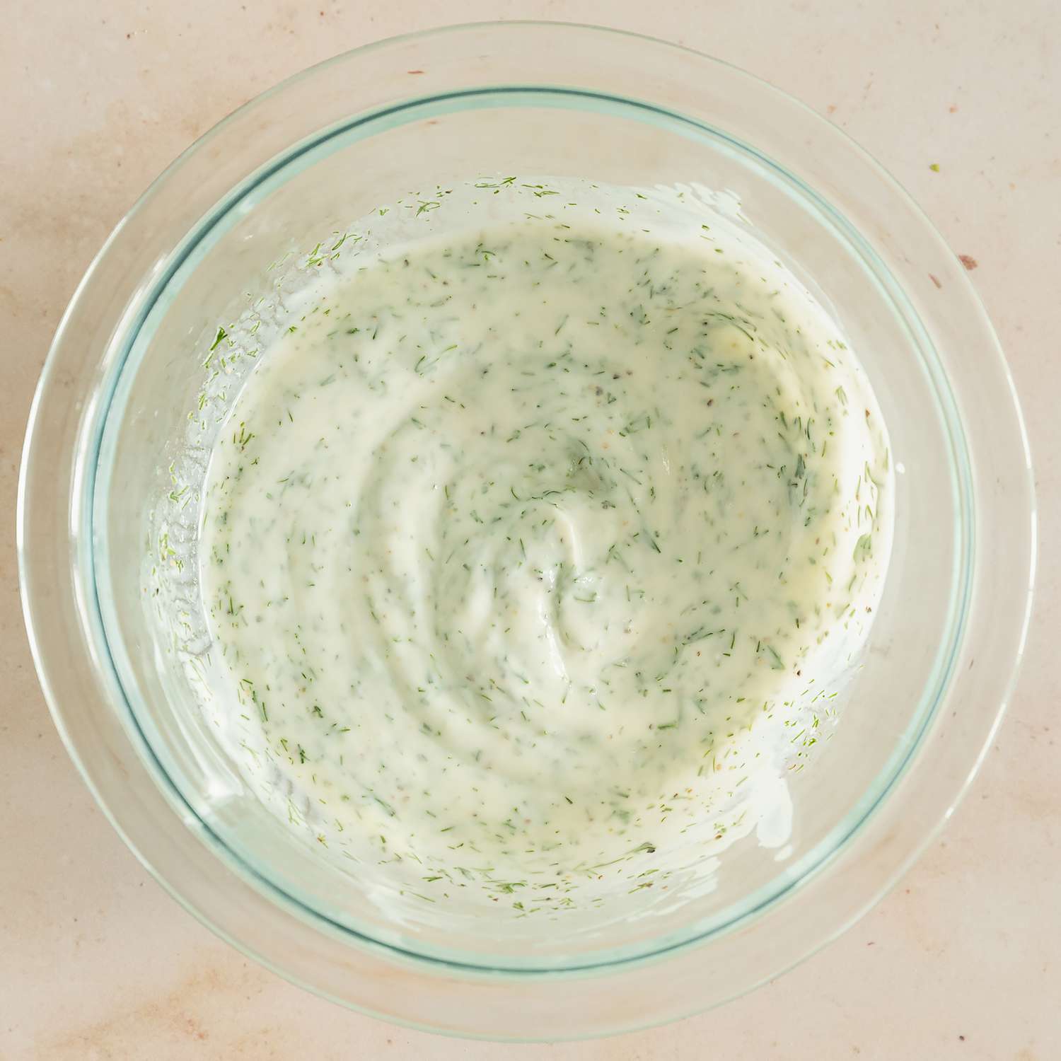 Overhead view of a clear glass bowl of dill dressing from Composed Salad with Pickled Beets & Smoked Tofu recipe