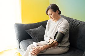 An older lady measuring blood pressure at home while sitting