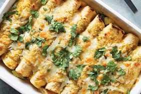 A dish of baked enchiladas with green herbs on top