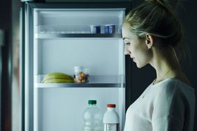 Woman standing in front of open refrigerator
