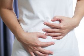 woman holding her midsection as if she is having digestion problems