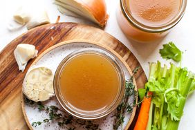 photo of beef bone broth in clear bowl with carrots and celery