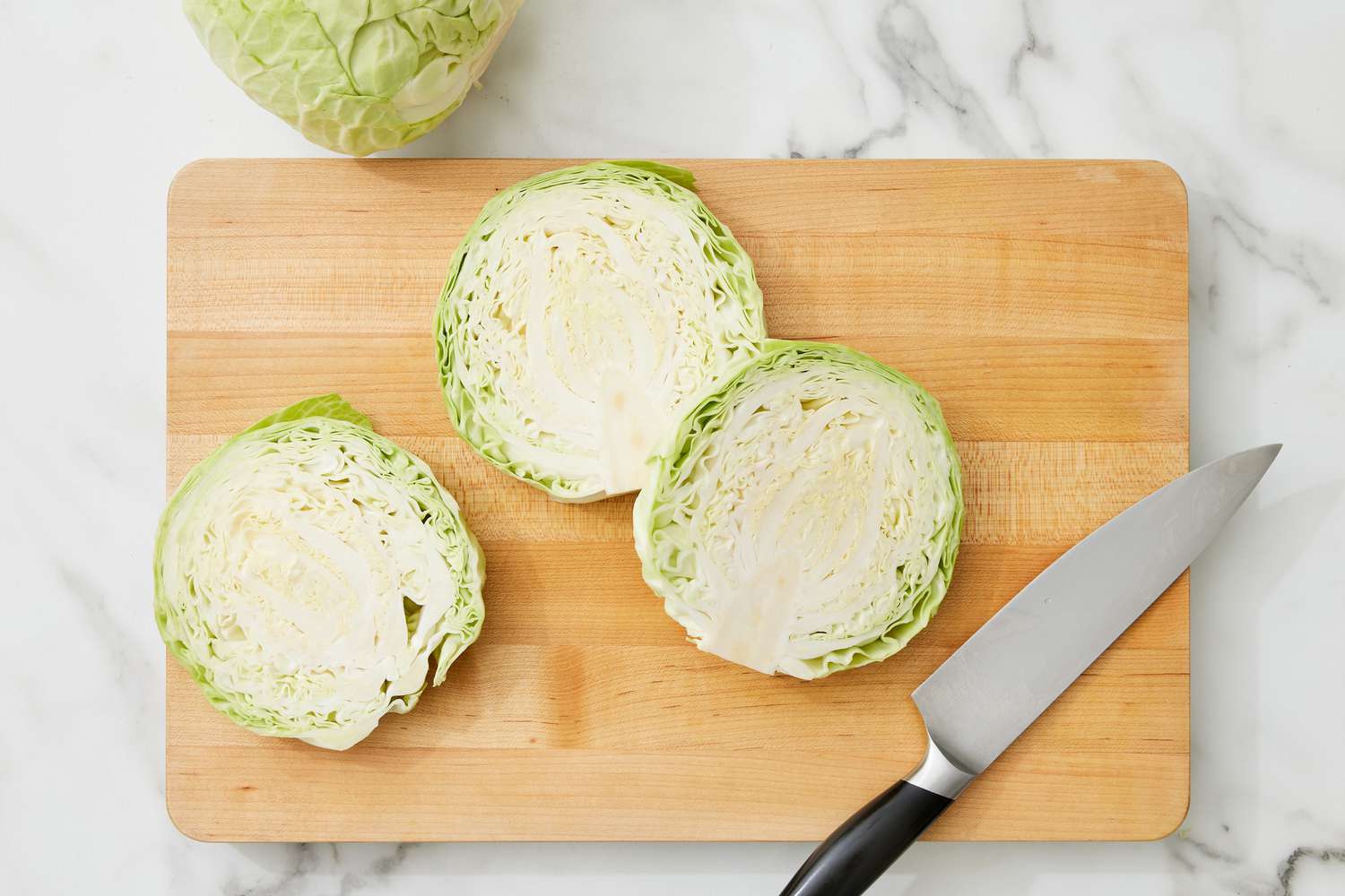 large, thick slices of cabbage on a cutting board with a knife