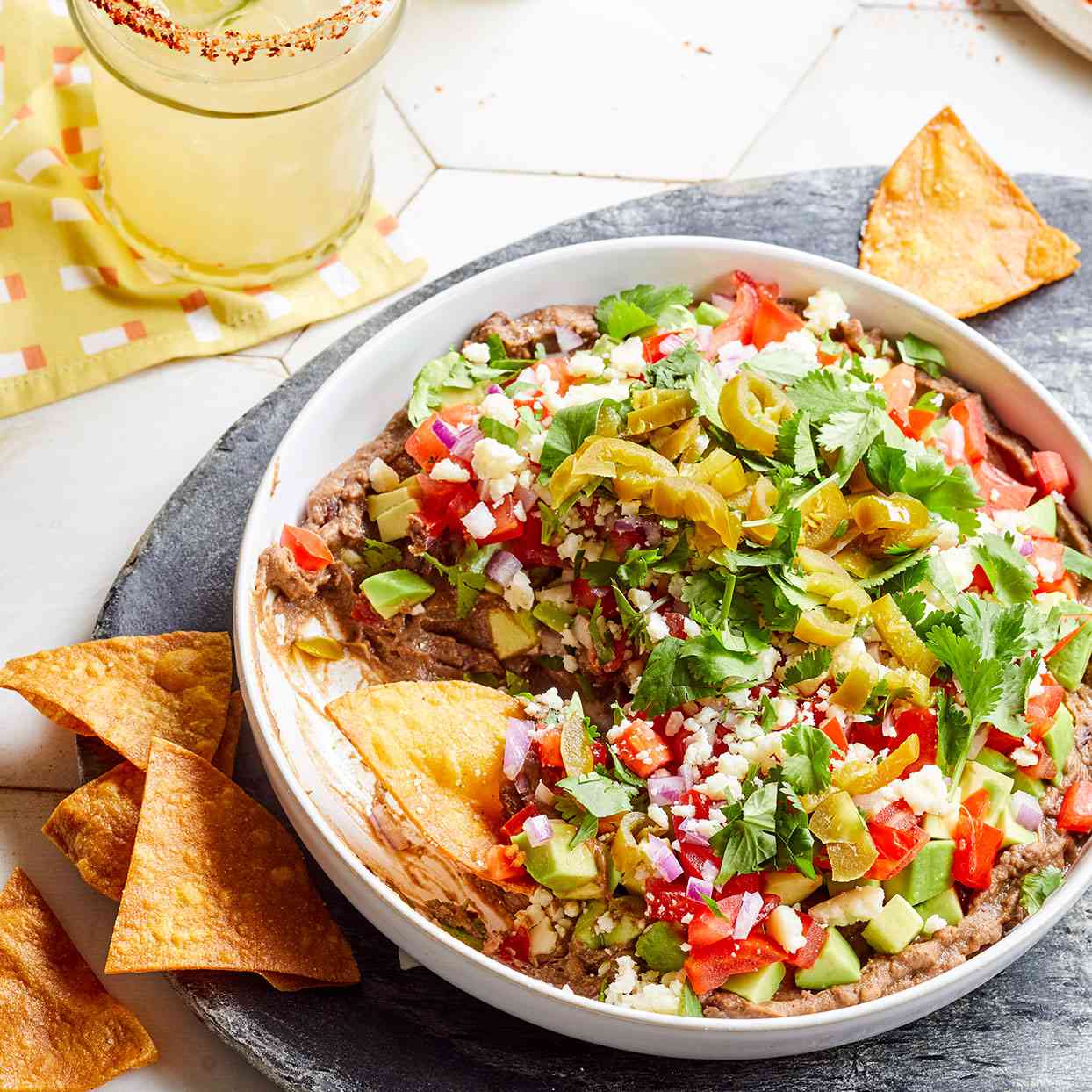 loaded black bean dip in a white bowl served with tortilla chips